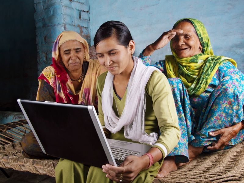 Women in India gather around a laptop. Image: iStock