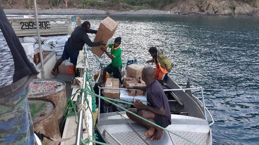 Four people loading boxes onto a boat.