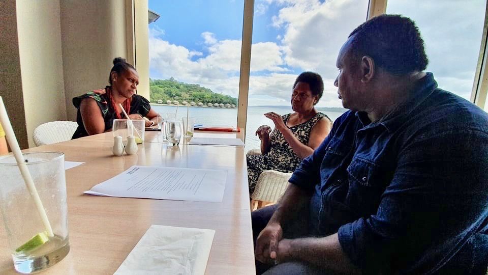 Three people in discussion around a table