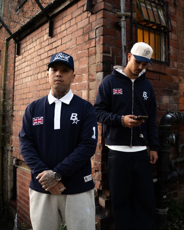 Two models in navy rugby shirts against a brick wall, shot for Best