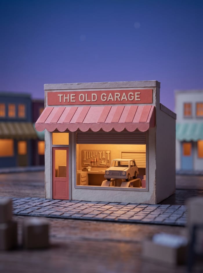 A model garage with a coral awning, doors up and a car on the ramp.