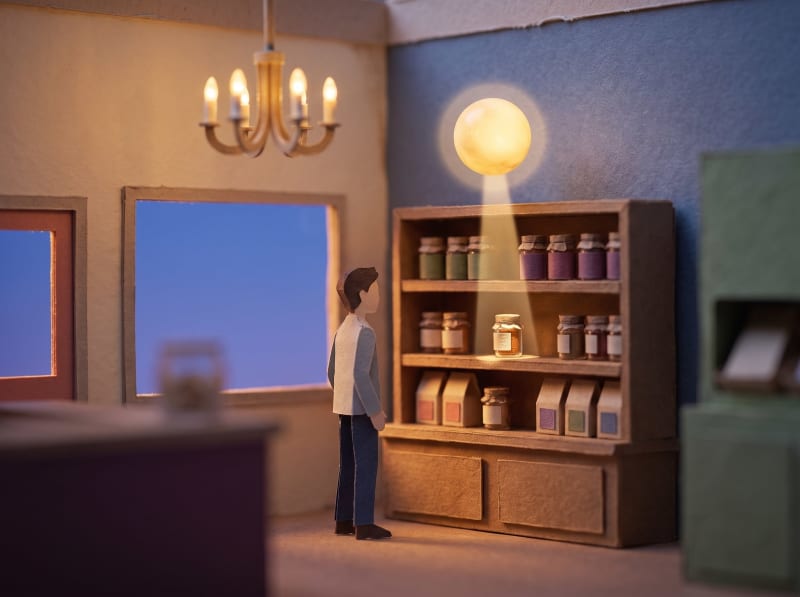 A paper shopper at a shelf, lit by a small floating orb picking out one item.
