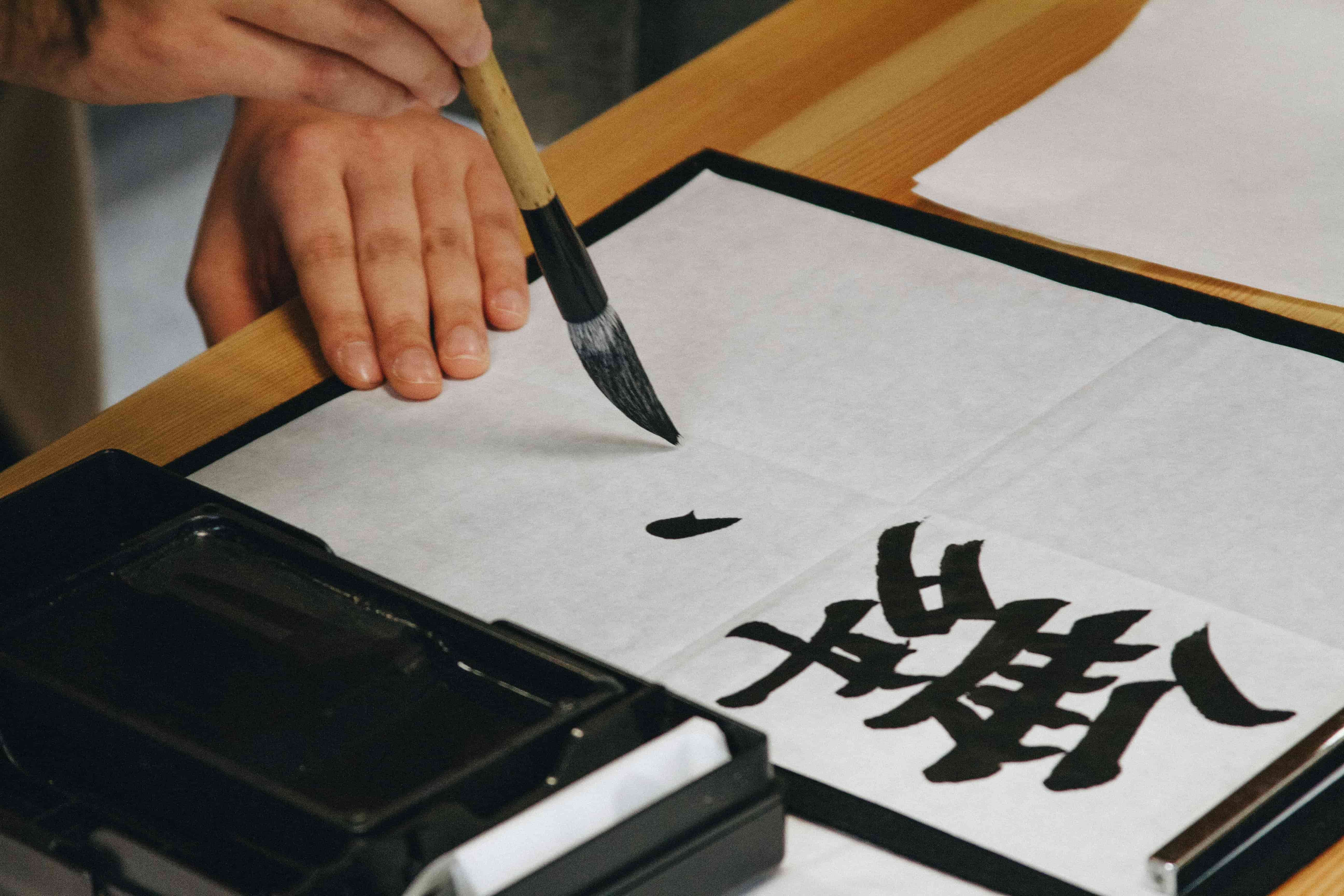 Close-up of a calligrapher practicing basic strokes, showing the contrast between thick downstrokes and thin upstrokes.