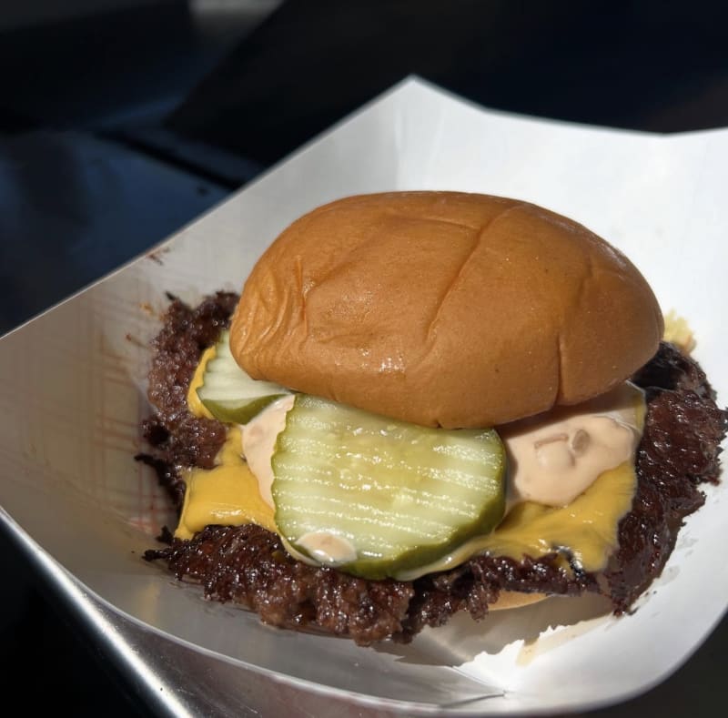 The Big Ugly: a double smash burger with a lacy crust, American cheese, pickles, and Ugly sauce on a potato bun in a paper boat