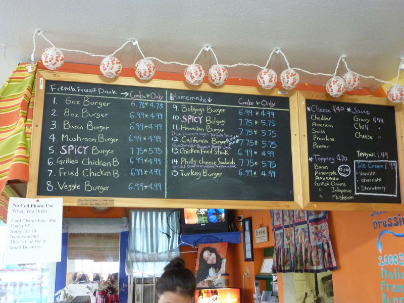 The Burger Tex chalkboard menu under a string of paper lanterns, listing fifteen burgers with the Bulgogi Burger at number nine