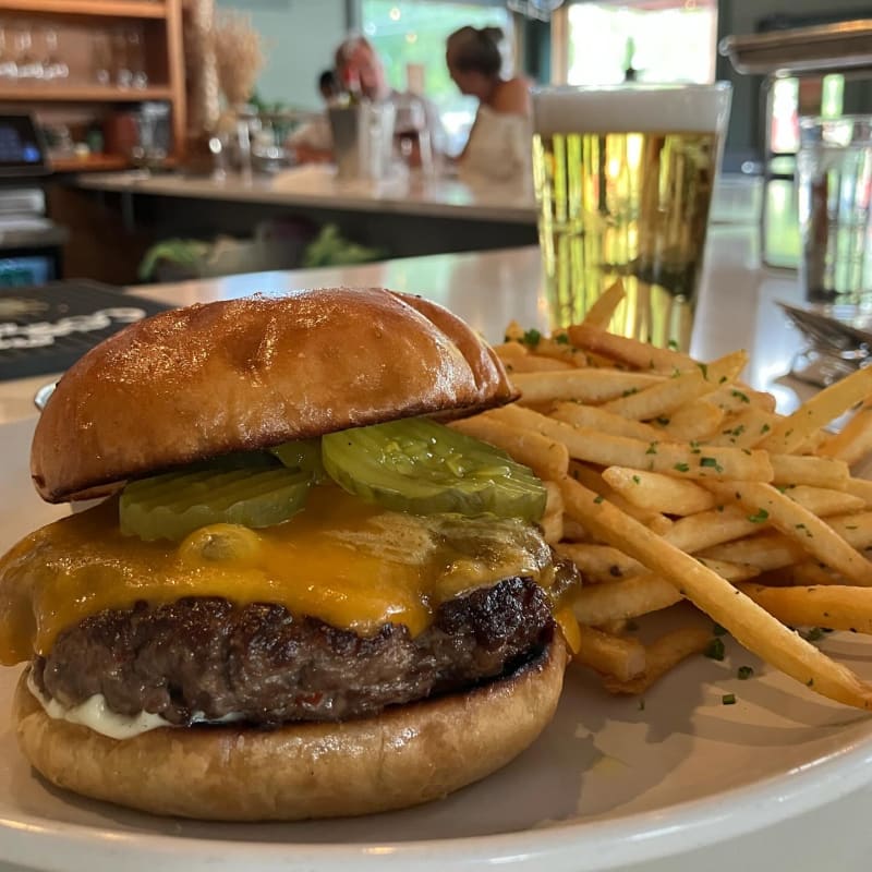 The Butcher's Burger at Salt & Time: a thick patty with melted cheddar, pickles, and aioli on a brioche bun, with beef-fat fries and a beer at the counter