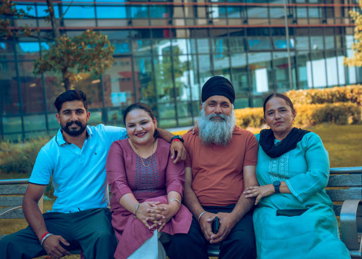 The family of four on a bench, arms around each other