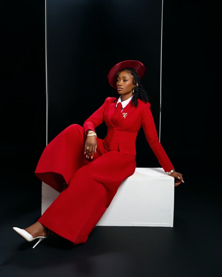 The red suit on the plinth, leaning back on one hand, legs crossed