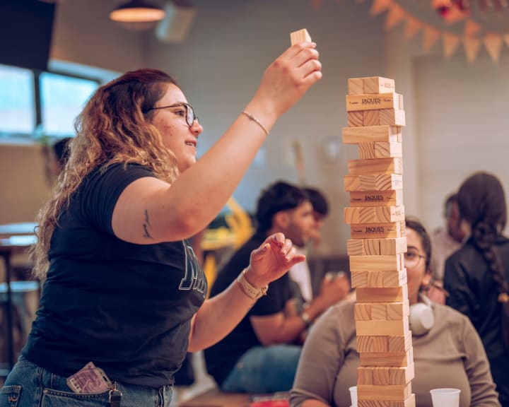 A Jenga tower almost as tall as the student reaching for it