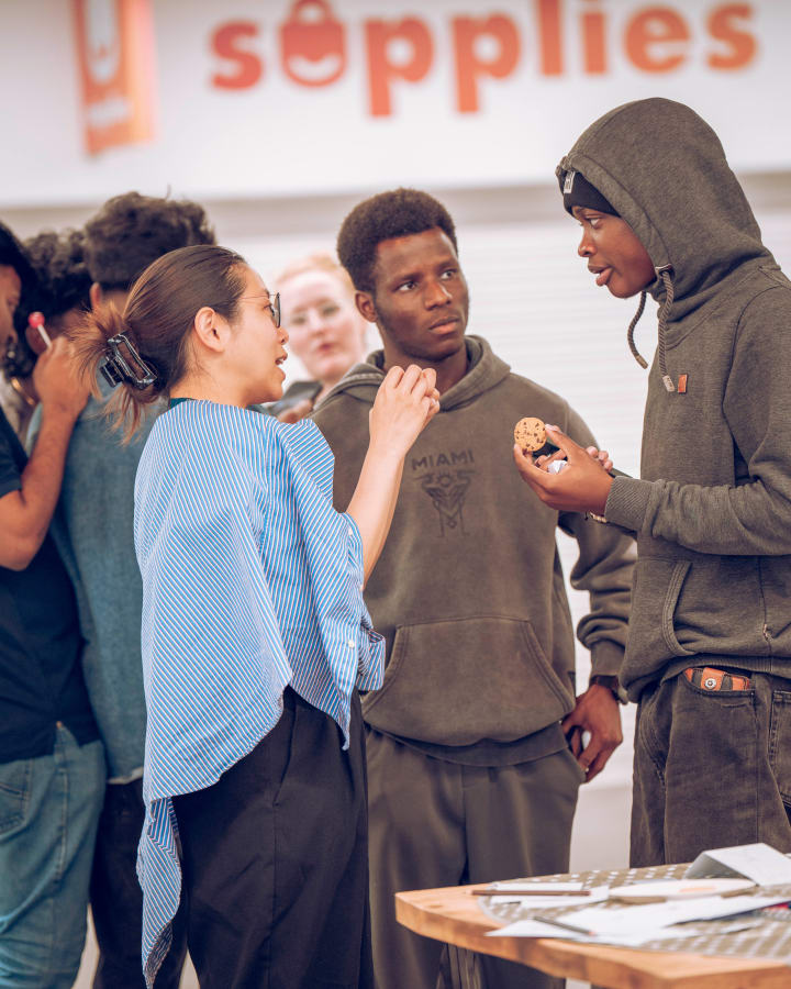 Two students talking under the Supplies sign
