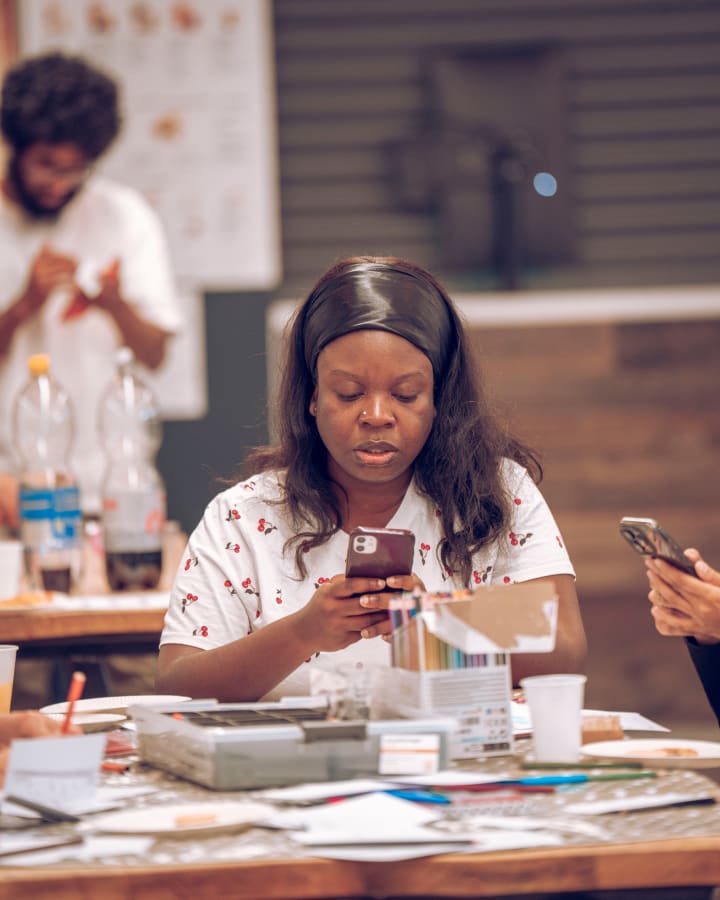 A student at a table with her phone, smiling