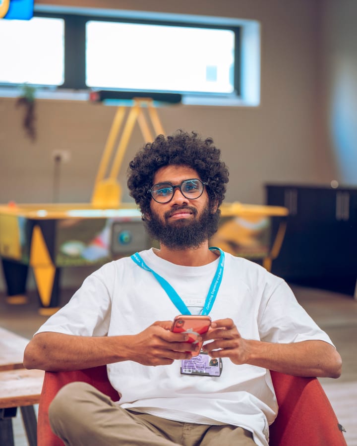 A student seated with his lanyard, smiling