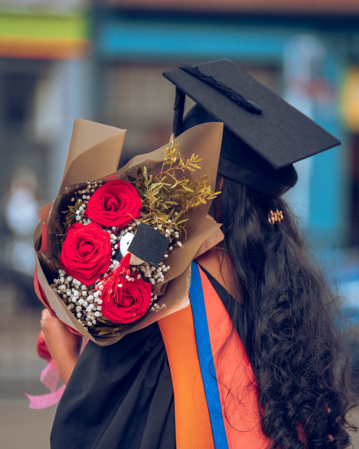 Red roses tucked under a mortarboard, from behind