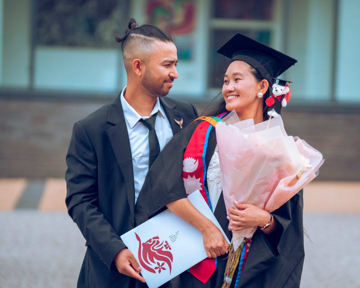 A graduate and a friend, flowers between them