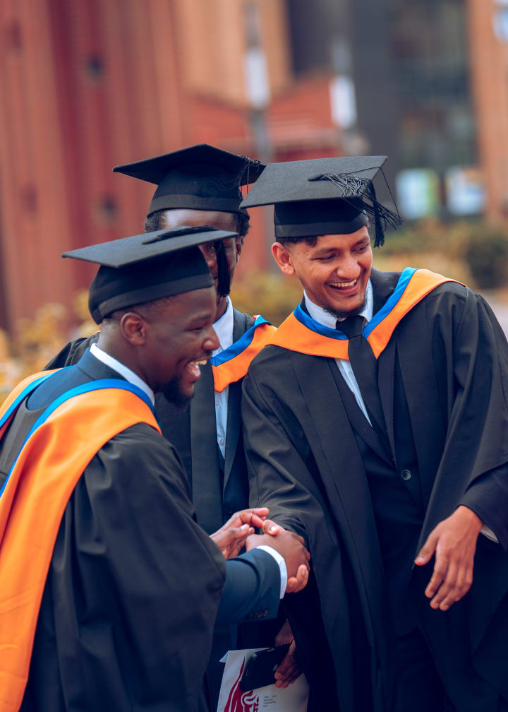 Graduates hugging in a huddle, caps touching