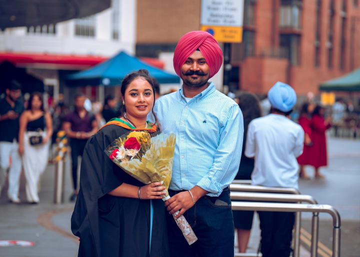 A graduate and his father with a bouquet, at the end of the day