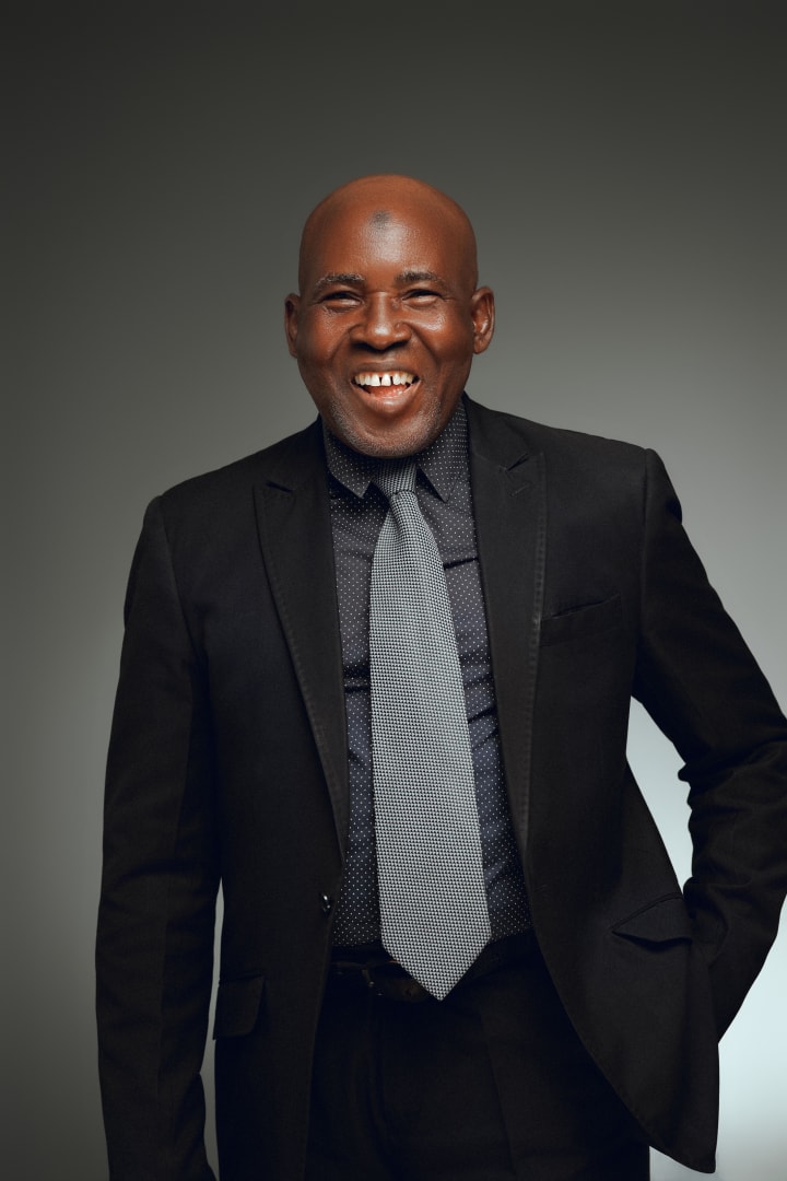 In a black suit and grey tie, laughing