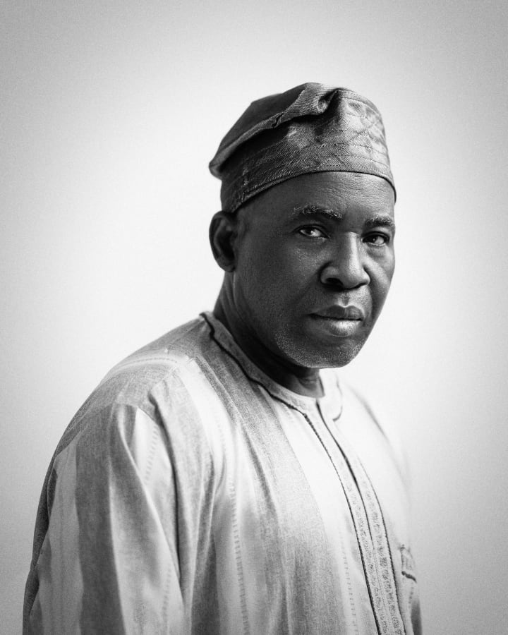 Dr. T.H. Dindi in a blue cap and white agbada, in grainy black and white