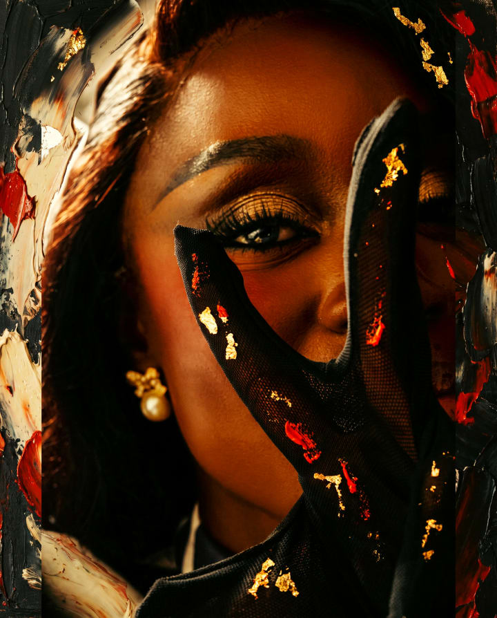 Ejiro's eye framed by a gloved hand flecked with gold leaf