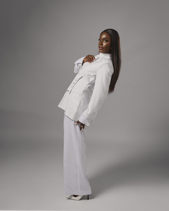 The white pinstripe suit, leaning back, one hand at the collar