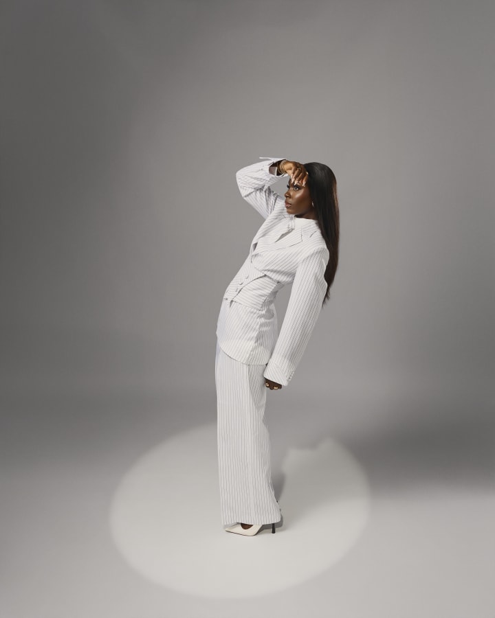 The white pinstripe suit, one hand on her head, in a pool of light