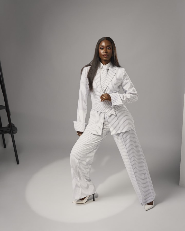 The white pinstripe suit, a wide stance, one hand at the chest