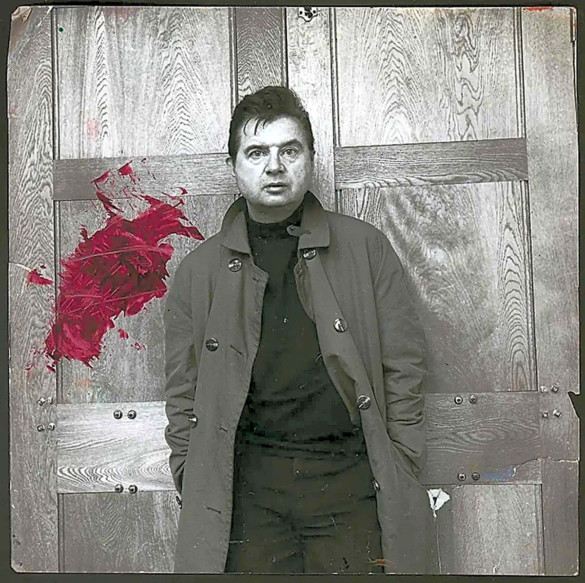 Retrato em preto e branco de Francis Bacon, pintor irlandês, com expressão sombria e olhar penetrante, vestido com terno escuro.