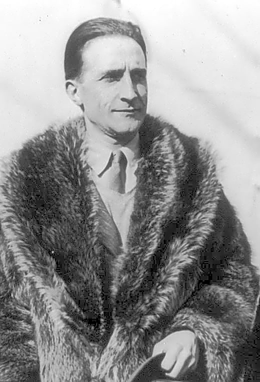 Pintura abstrata em tons de azul e cinza, retratando a silhueta de Marcel Duchamp sentado em uma cadeira, com objetos surreais ao redor.