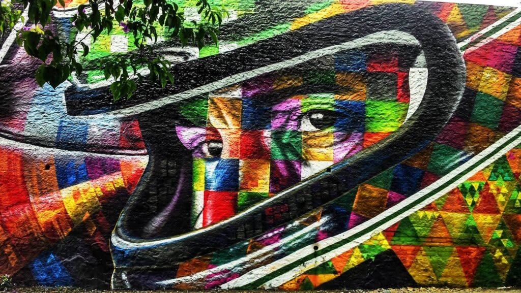 Biografia de Eduardo Kobra - A lenda do Brasil: Realizada em 2.015, a pintura está localizada na lateral de um prédio da Rua Consolação, perto da Avenida Paulista na região central de São Paulo. Tem 41 metros de altura.  Em 2.016, o muralista pintou o mito Ayrton na região dos Arcos da Lapa no Rio de Janeiro e em 2.019, por ocasião dos 25 anos da morte do grande ídolo brasileiro, Kobra recebeu uma encomenda para retratar Senna no autódromo de Ímola onde o piloto brasileiro faleceu.