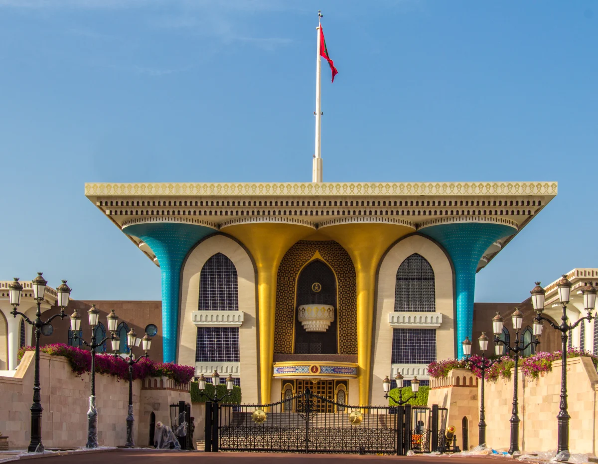 Die Fassade des Al-Alam-Palastes mit ihren ausgestellten blauen und goldenen Säulen, vom Platz aus gesehen