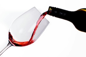 A large wine glass being filled from a bottle of red wine