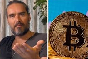 Russell Brand on one side of the image holding his hand to the camera, and a gold bitcoin coin upright in the desert