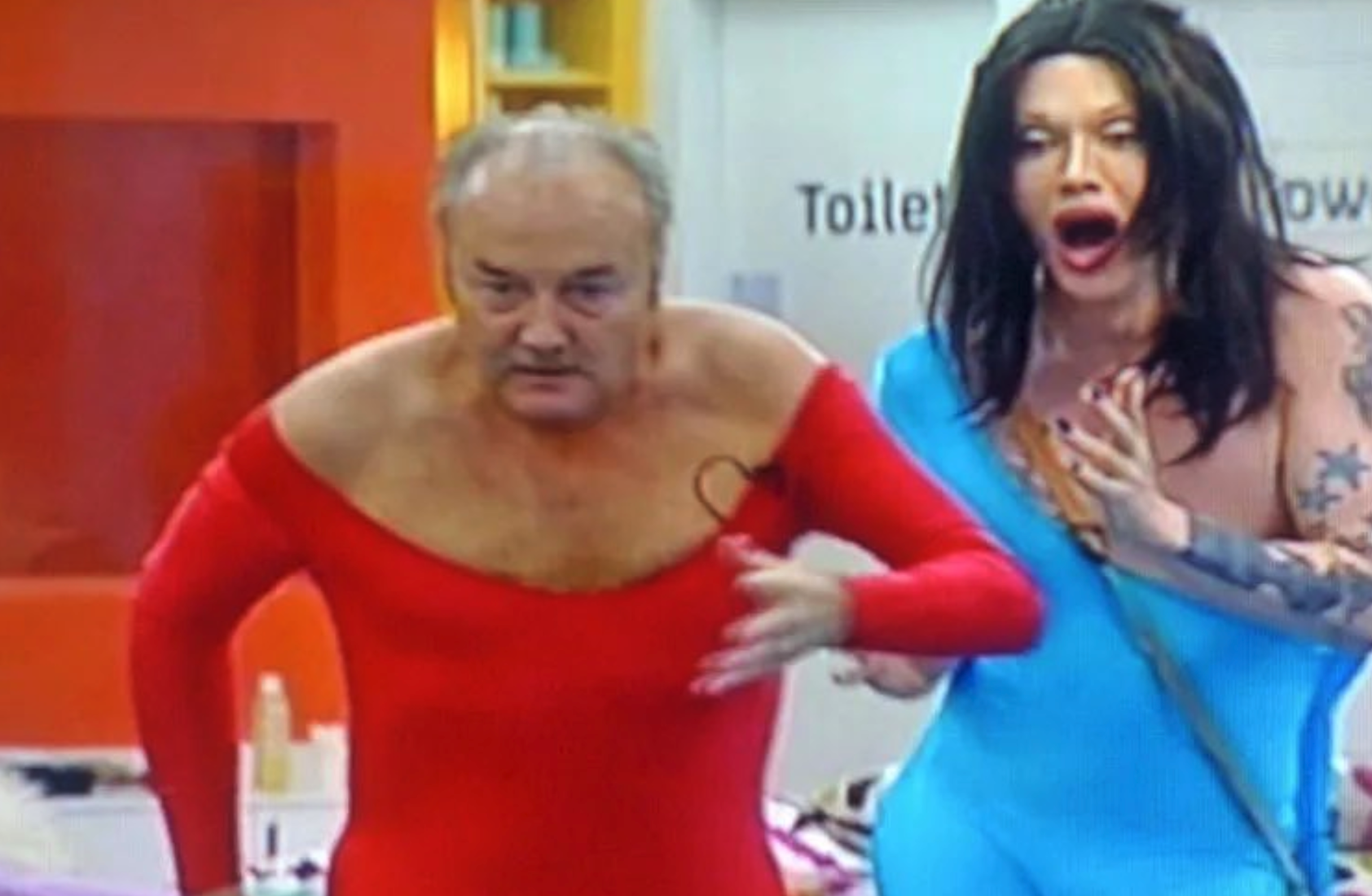 George Galloway showing some cleavage dressed in a tight red spandex, with Sandra Dickinson behind him with her mouth wide open