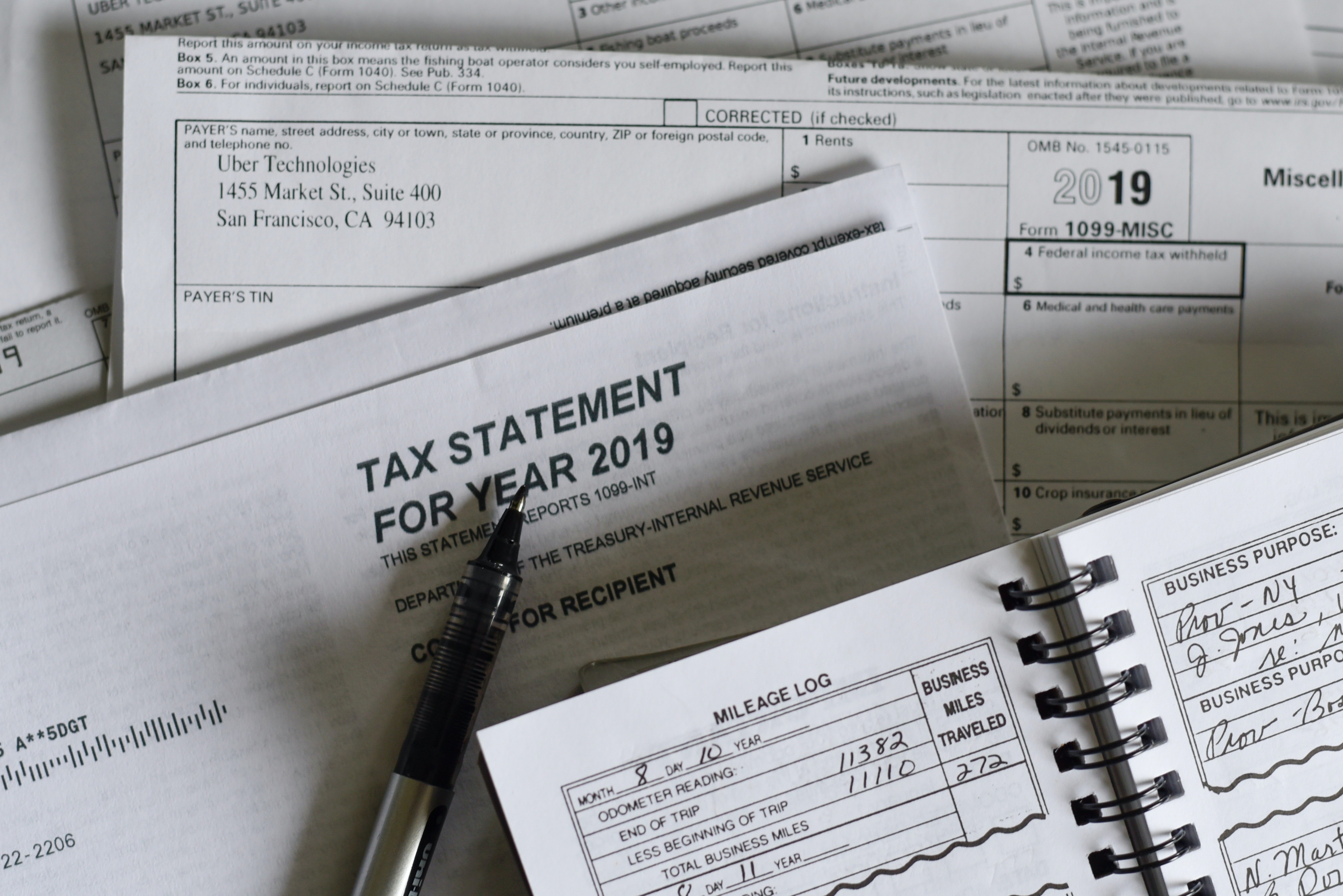 a pile of tax documents with a pen on top