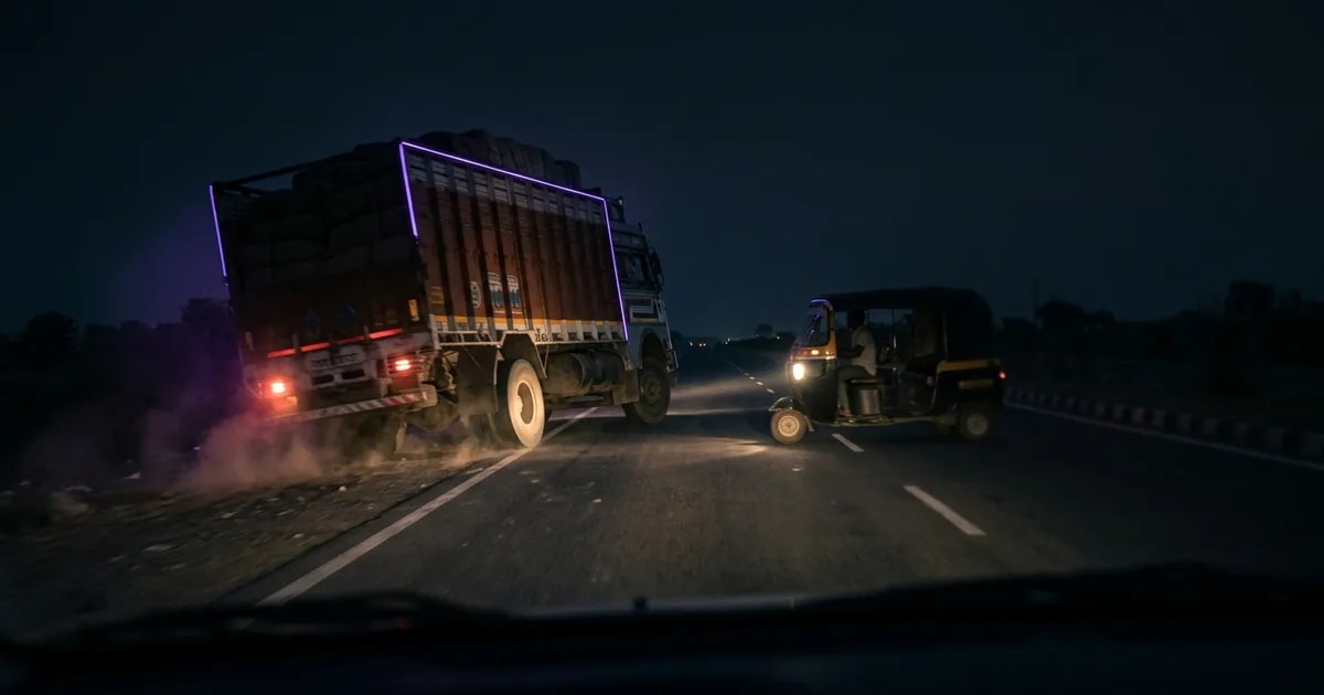 A truck driver's view of a highway in India, with an AI dashcam interface overlaid showing safety alerts