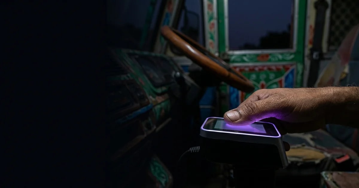 A fleet manager using a tablet to verify a truck driver's documents in a busy Indian transport yard