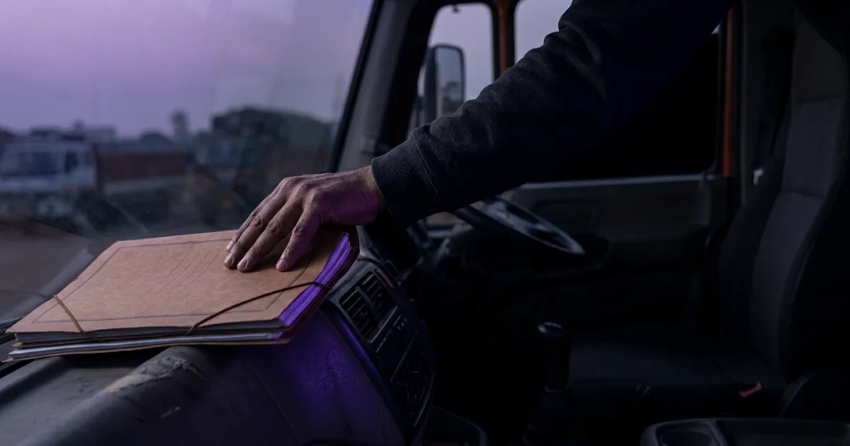A fleet manager reviewing a fleet insurance claim document checklist on a tablet in front of a truck.