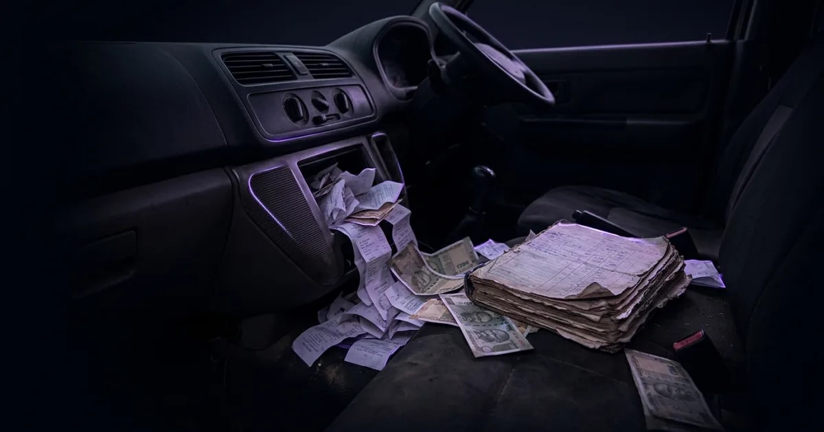 A transport manager reviewing driver expense receipts on a computer screen next to a truck.