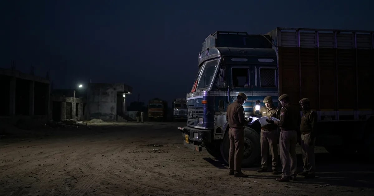 A commercial truck being inspected by an RTO officer on an Indian highway