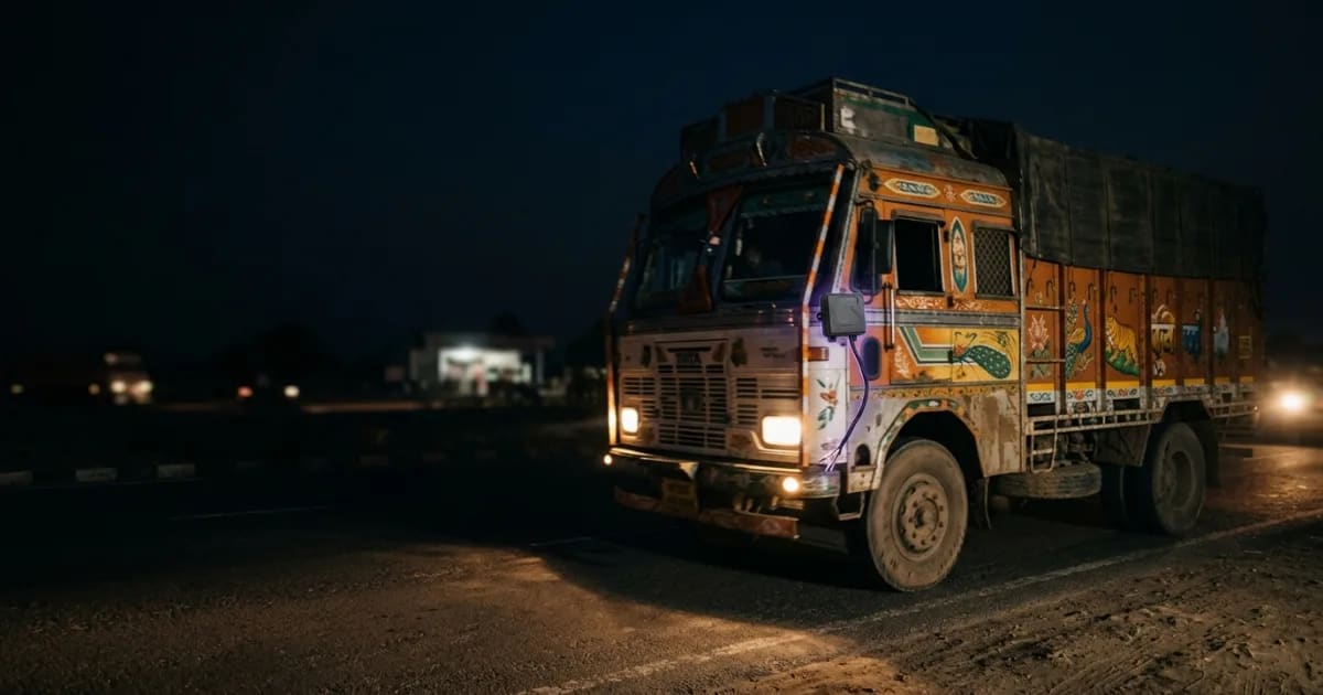 A truck on a map with a broken data connection icon pointing to a government building, representing AIS-140 data gaps to the Vahan portal