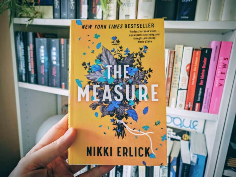 Hand hält Buch vor einem Bücherregal