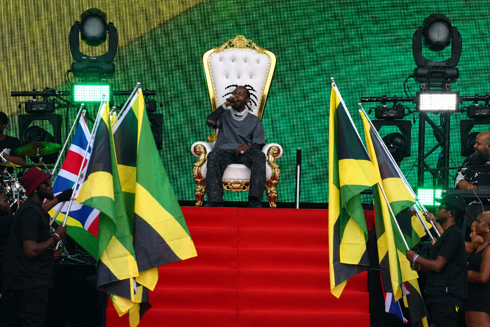 Popcaan on stage surrounded by Jamaican flags during a major performance moment