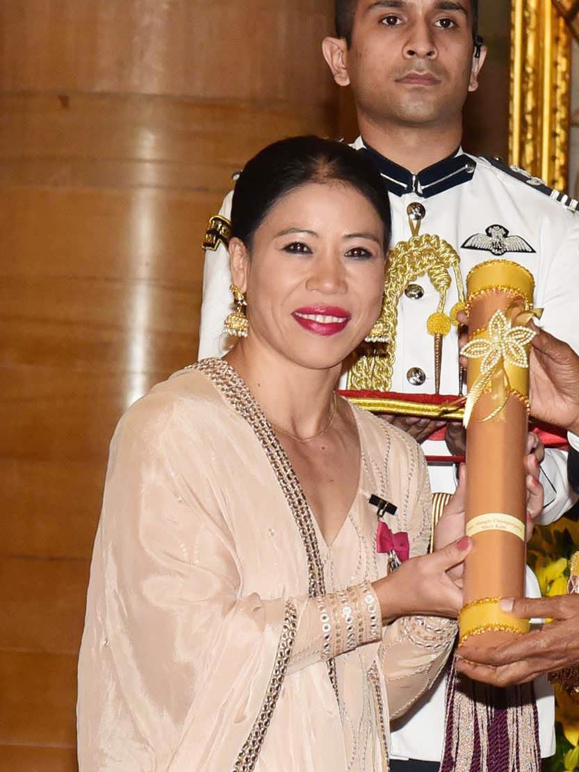 Boxer Mary Kom smiling in a peach embroidered outfit while receiving the Padma Vibhushan scroll at Rashtrapati Bhavan