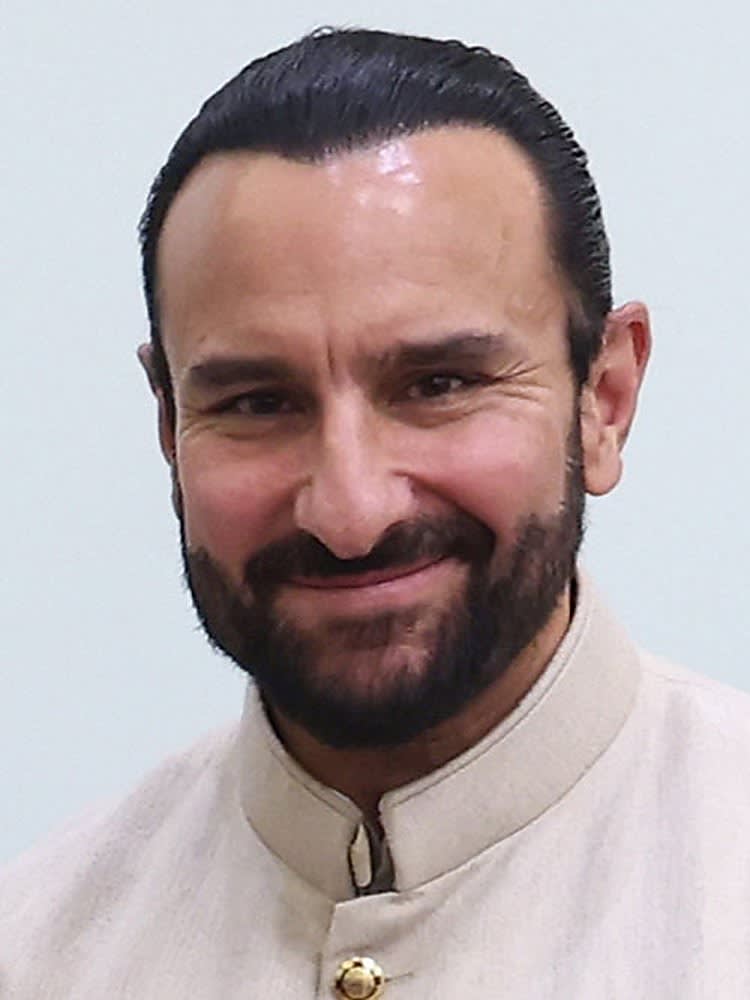 Actor Saif Ali Khan with a beard, in a cream high-collar jacket, smiling at the camera in 2024