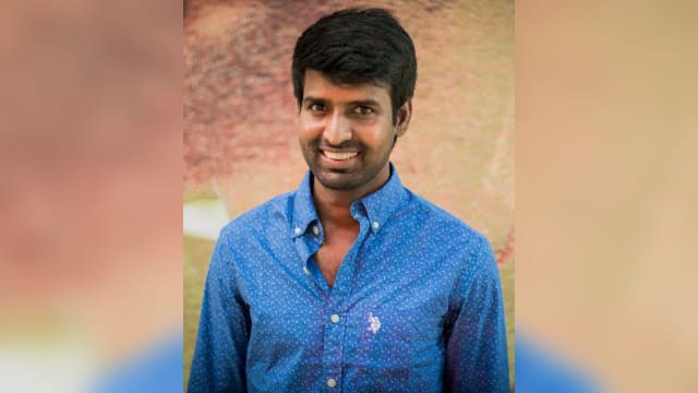 Actor Soori smiling in a blue shirt at a press meet