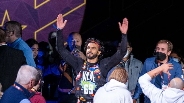 Ranveer Singh raising both arms and smiling as he walks out in an NBA jersey during the 2022 NBA All-Star Weekend