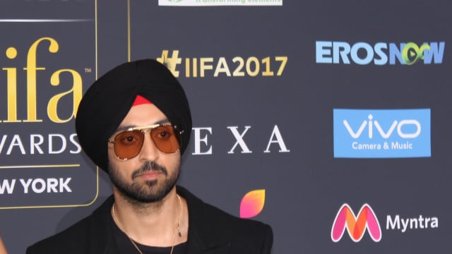 Diljit Dosanjh in a black turban, tinted aviator sunglasses and a black jacket in front of a logo backdrop at the IIFA 2017 green carpet in New Jersey