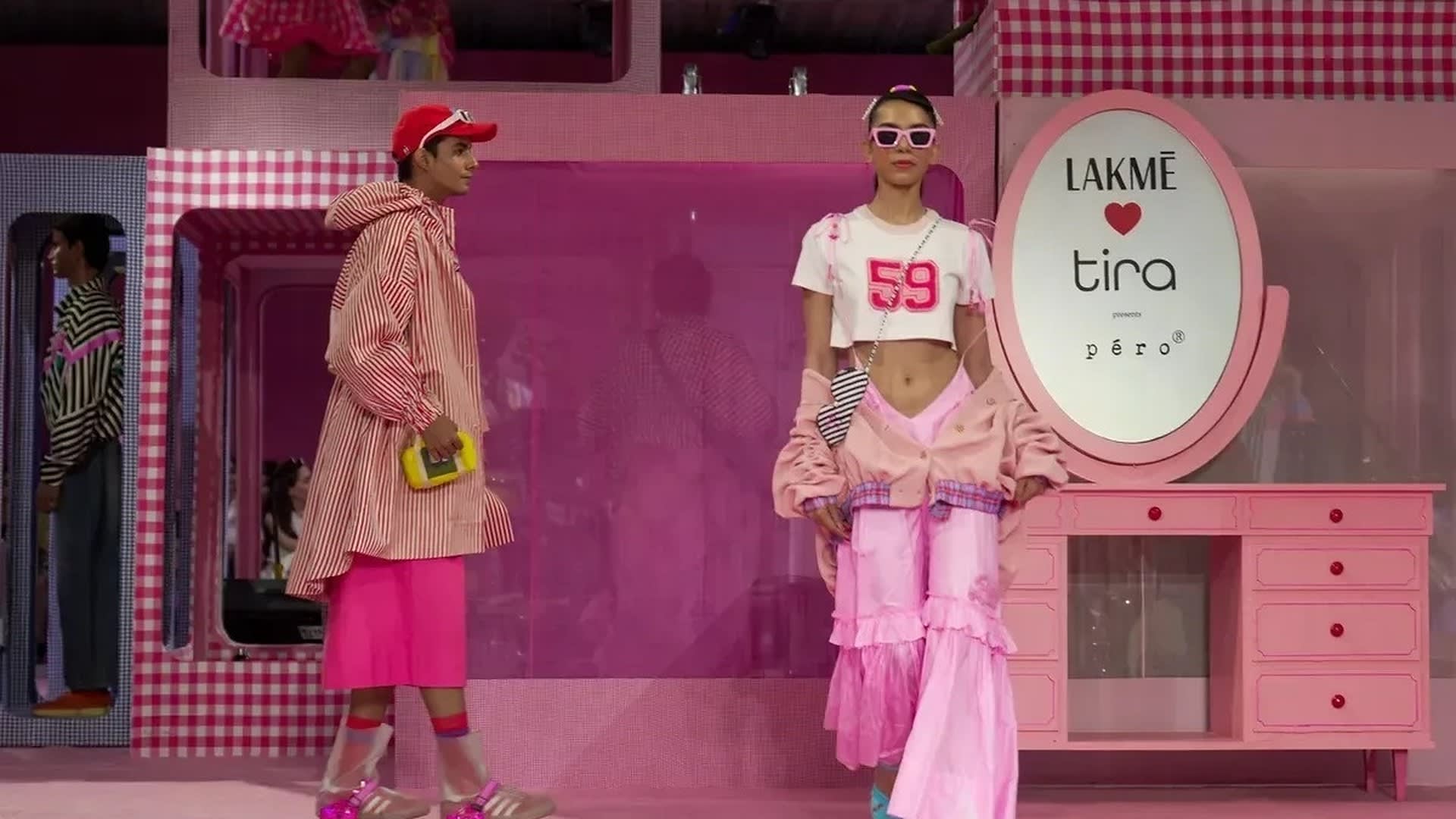 Models in Péro x Barbie Dream Dress-Up Spring/Summer 2027 looks, a red-striped coat and pink ruffled trousers, on the pink Barbie-box set at Lakmé Fashion Week x FDCI, New Delhi, 14 October 2026