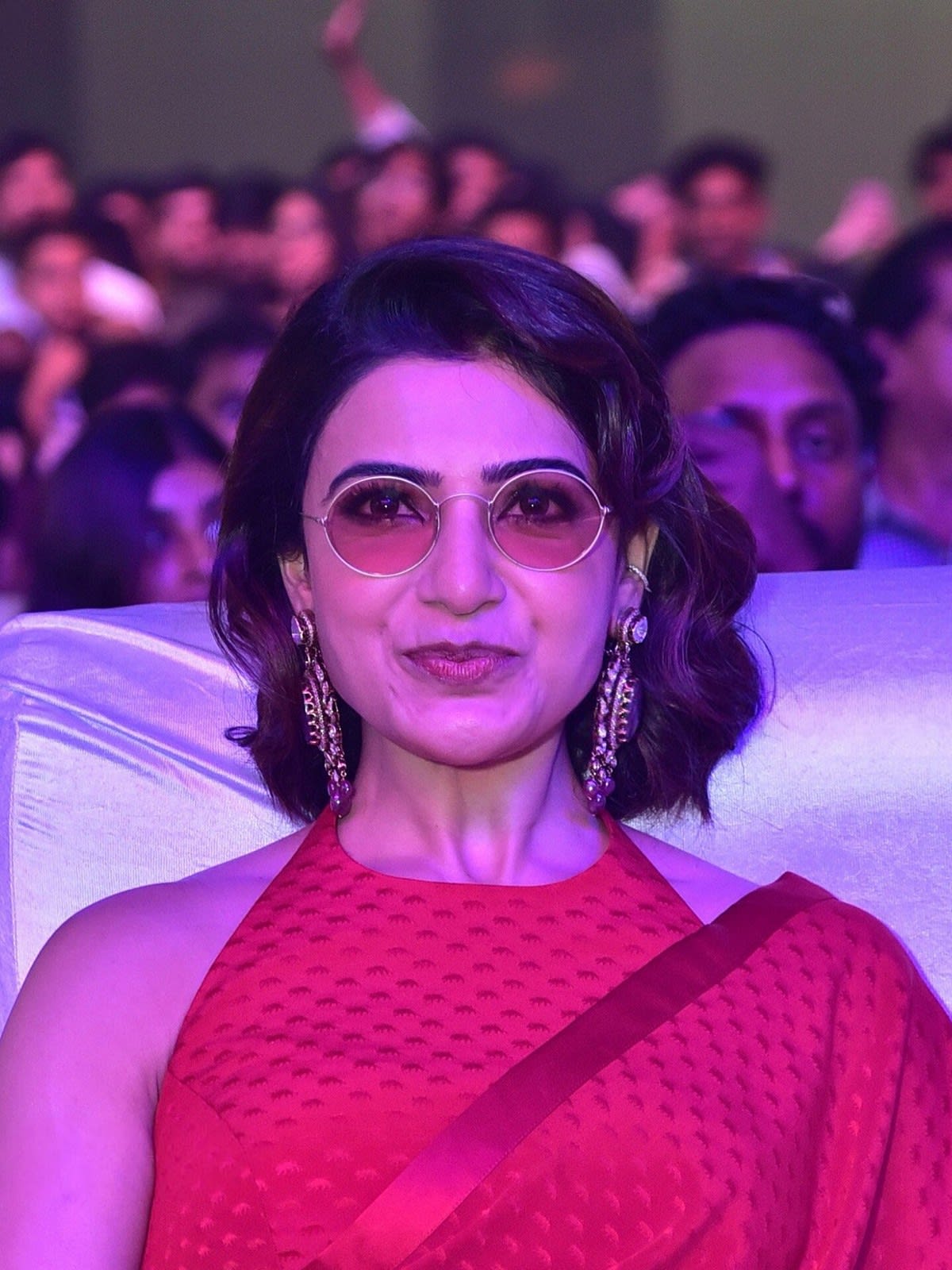 Samantha Ruth Prabhu with short curly hair and tinted glasses, smiling in a red saree at the Kushi musical concert in 2023