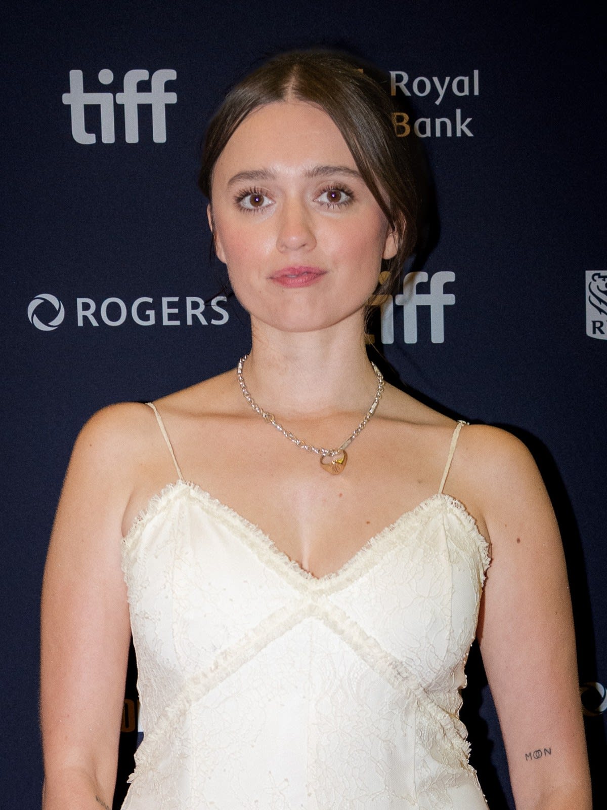 Aimee Lou Wood with her hair in a short bob, wearing a white slip dress and a delicate pendant necklace at the TIFF 2026 premiere of The Idiot(s)